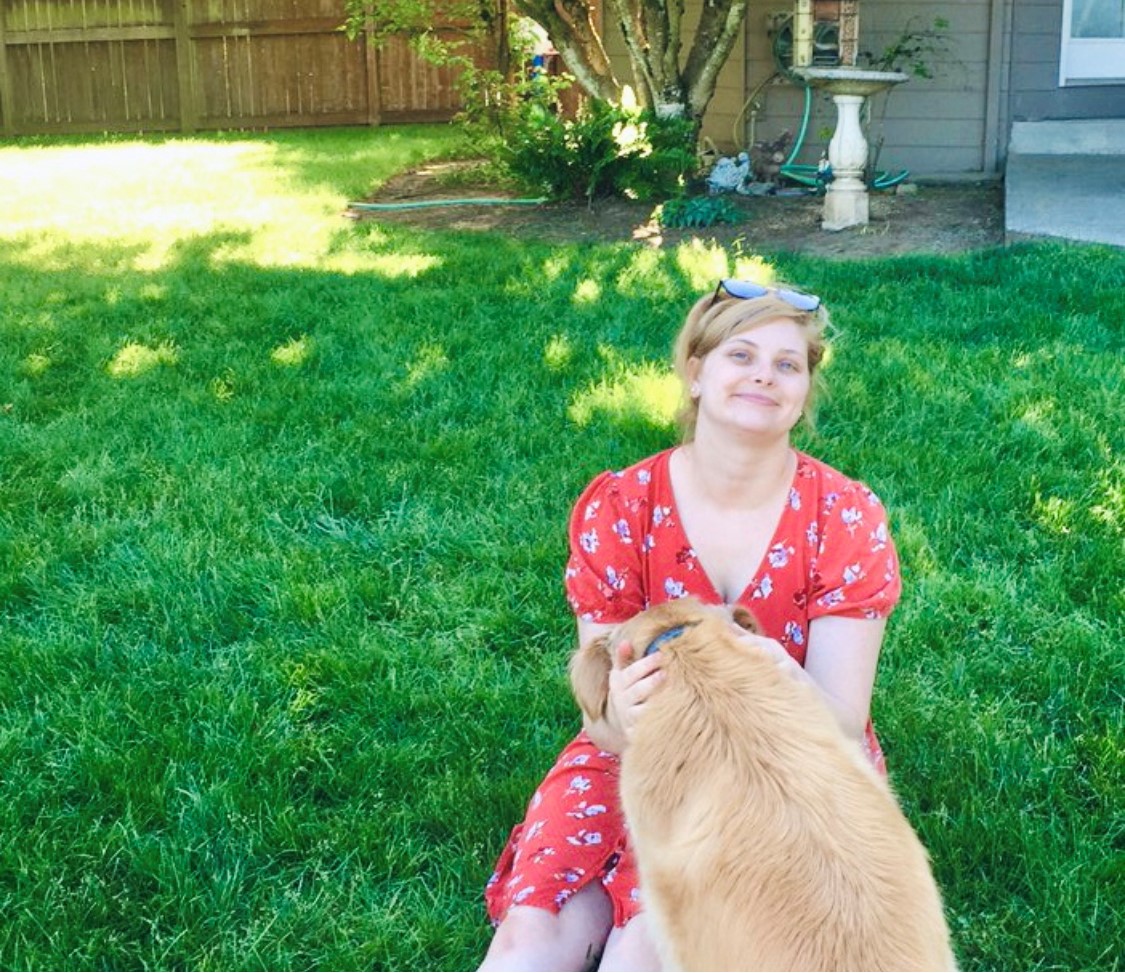 Steph sitting outside with her sister's golden retriever in her lap.